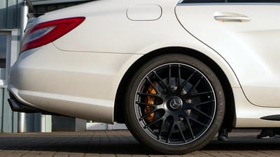 Original-Felge am Mercedes-Benz CLS 63 AMG Weißer Mercedes-Benz CLS 63 AMG mit goldenen Bremssätteln und schwarzen Original-Felgen im Vielspeichen-Design