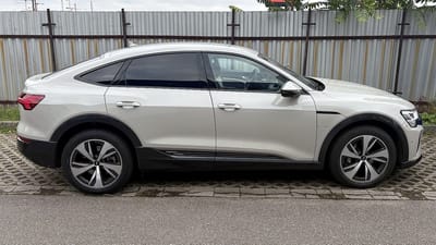 Audi Q8 Sportback e-tron mit Original-Felgen von OR24.de Audi Q8 Sportback e-tron in Weiß vor einem Wellblechzaun, Seitenansicht mit glanzgedrehten Original-Aerofelgen