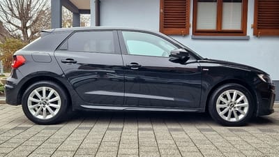 Audi A1 mit Original-Felgen von OR24.de Seitenansicht eines schwarzen Audi A1 mit S-line-Emblem am Kotflügel und silbernen Original-Felgen im 10-Speichen-Design