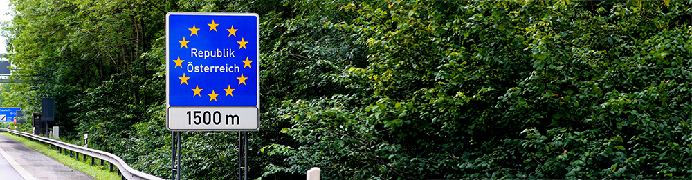 Grenzübergang Österreich: Wichtige Informationen für Autofahrer Straßenschild mit EU-Sternen und der Aufschrift 'Republik Österreich', 1500 Meter vor der österreichischen Grenze, umgeben von grüner Natur